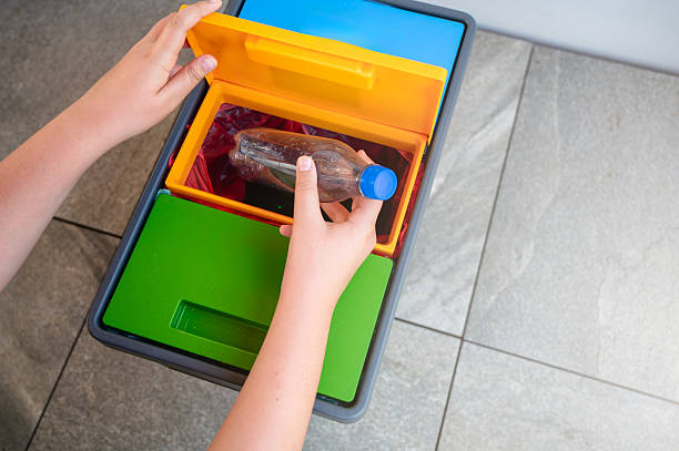 istock Close-up of a person’s hands sorting waste, placing a plastic bottle into a color-coded recycling bin at home, promoting environmental awareness and sustainable living 2225553936