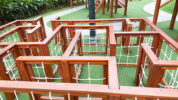 istock Solo indonesia 07.15.2025 This image displays a brown wooden maze structure with white rope netting, set on a bright green artificial turf. It's an engaging feature within a playground, designed for children's exploration and fun. 2225557610