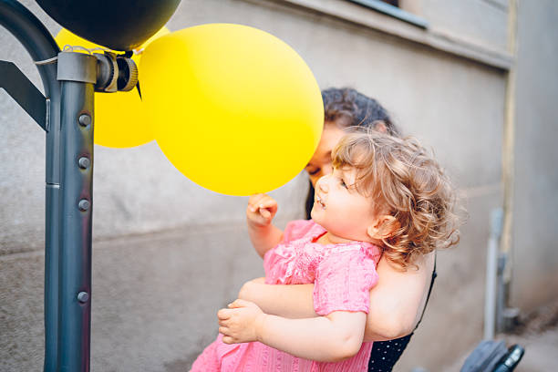 Mother enjoy with daughter in embracing. Mother holding her baby . They playing with balloons.