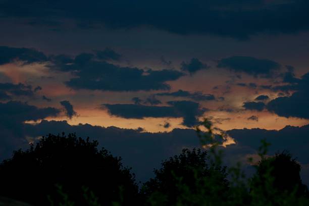 Dramatic evening sky with layered dark clouds and soft pastel hues from the setting sun. A peaceful, moody atmosphere perfect for nature, weather, or twilight-themed visuals.