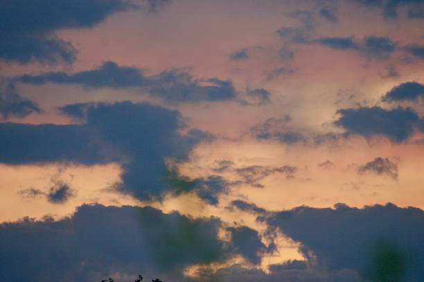 istock Dramatic evening sky with layered dark clouds and soft pastel hues from the setting sun. A peaceful, moody atmosphere perfect for nature, weather, or twilight-themed visuals. 2225562150