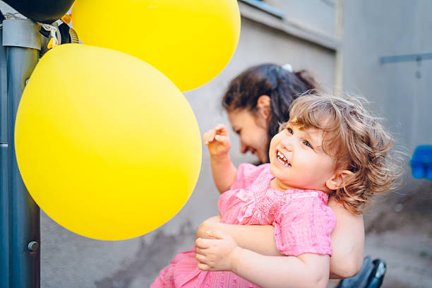 Mother enjoy with daughter in embracing. Mother holding her baby . They playing with balloons.