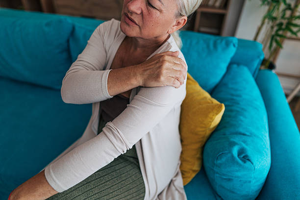 istock Senior woman suffering from shoulder pain while sitting on sofa 2225565417
