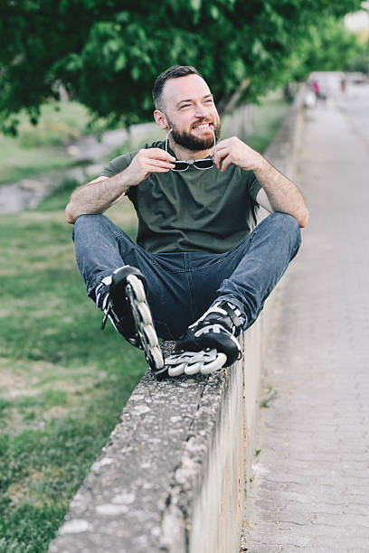 Cool Male Resting With Rollerblades After Early Workout in City