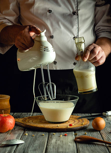 istock A chef is using a hand mixer to blend a creamy mixture in a bowl while holding a bottle of milk in a rustic kitchen. Fresh ingredients are nearby, enhancing the atmosphere 2225568059