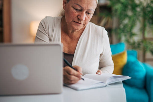 istock Senior adult woman taking notes while working from home 2225568112