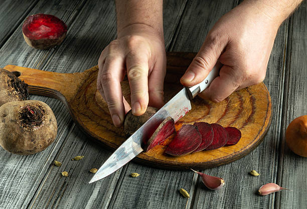 istock In a rustic kitchen, hands skillfully slice vibrant beets on a wooden cutting board while garlic cloves and spices create a flavorful atmosphere nearby 2225568380