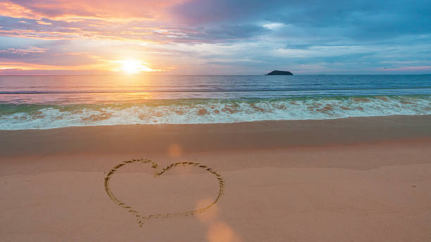 istock Heart shape on sand beach at sunset sea background 2225572482