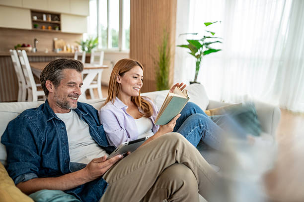 istock Couple relaxing on sofa, reading and using digital tablet at home 2225572684