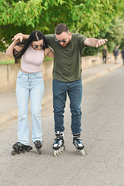 istock Girlfriend Holding Boyfriend Steady and Laughing While He's Struggling to Rollerblade 2225579499
