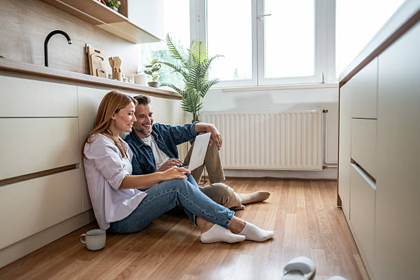 istock Couple sitting on kitchen floor browsing internet on laptop 2225580922