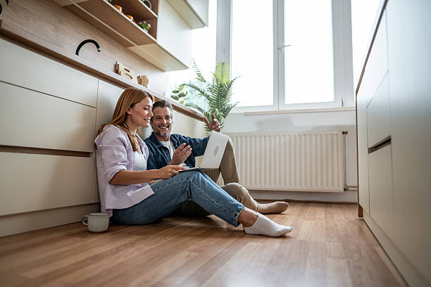 istock Couple using laptop and having a video call in their modern kitchen 2225580926