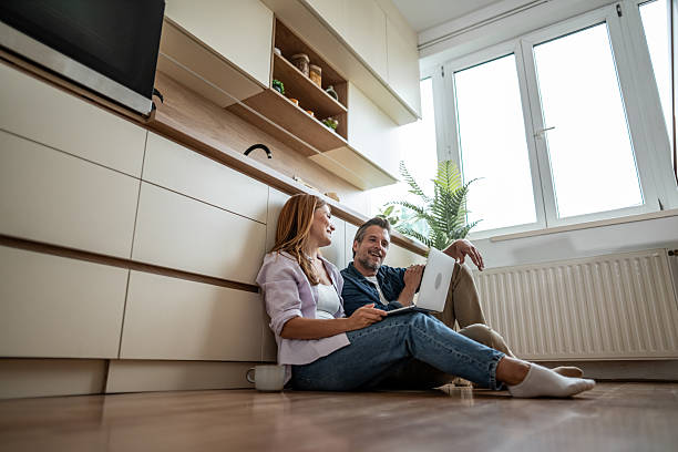 istock Couple sitting on kitchen floor browsing internet on laptop 2225580931