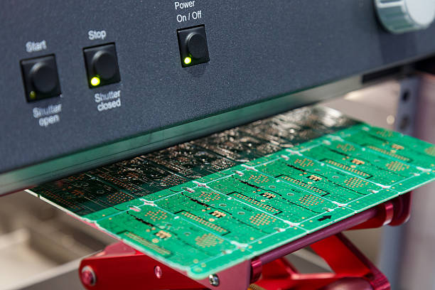 istock electronic circuit board under processing machine. Close-up of green PCB manufacturing stage with illuminated control panel. Electronic components production and assembly line. 2225582124