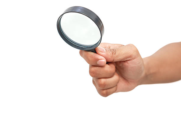 Hand holding a magnifying glass isolated on white background, a symbol of search, research