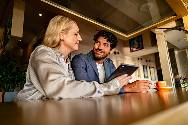 istock Coworkers talking and using digital tablet during meeting at coffee shop 2225583245