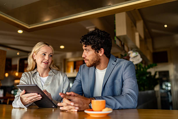 istock Coworkers talking and using digital tablet during meeting at coffee shop 2225583656
