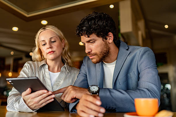istock Coworkers talking and using digital tablet during meeting at coffee shop 2225583707
