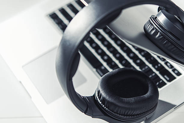 istock Modern Headphones Resting on a Silver Laptop Keyboard in a Bright Workspace Setting 2225584702