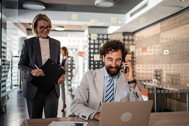 istock Businessman working on laptop and talking on phone in office 2225585009