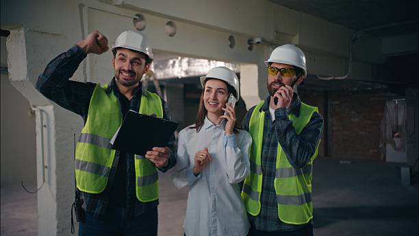 istock Happy Caucasian team engineers workers architects builders smile males win inspector female talking mobile phone handymen employees rejoice in factory colleagues men woman complete work plan good job 2225586525