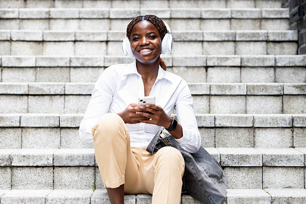 istock Fashionable black woman sitting on the steps and using smart phone. 2225590077
