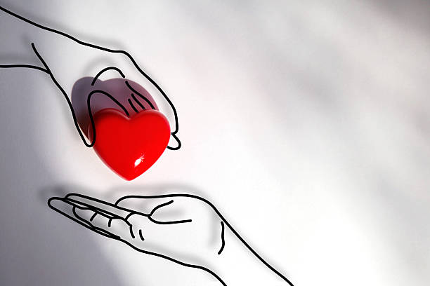 istock Minimalist concept image showing one illustrated hand passing a red heart to another, symbolizing love, kindness, giving, and emotional support, emotional storytelling, healthcare, community support visuals. 2225593703