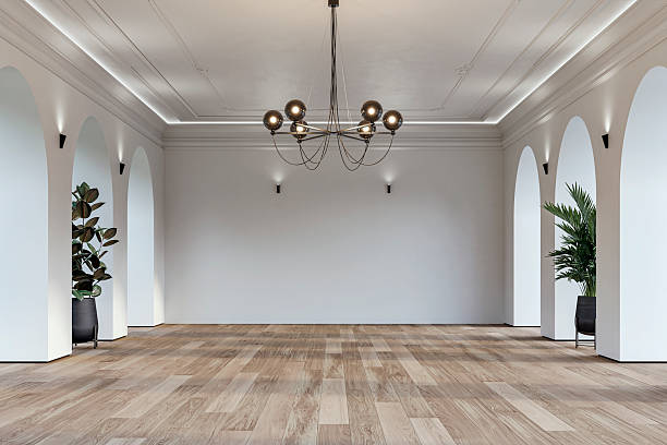 Modern empty interior with elegant arched openings, decorative ceiling molding, chandelier and decorative potted plants