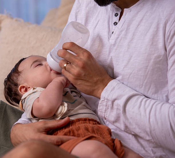 istock Father Comforting Baby During Bottle Feeding at Home. 2225595481