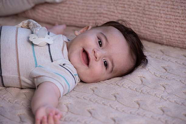 istock Cheerful Baby Reaching Out While Lying on Soft Blanket. 2225595564