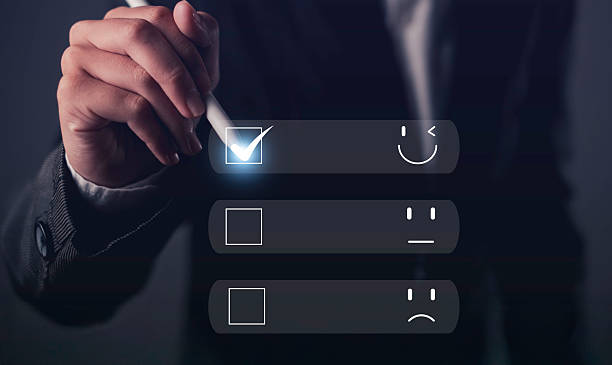 istock Hand holding stylus selecting happy face on digital satisfaction survey, representing positive feedback, customer experience, and user satisfaction. 2225595698