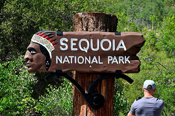 Three Rivers, California, USA - May 23, 2025: A man takes a photograph of the historic southern entrance sign to Sequoia National Park.