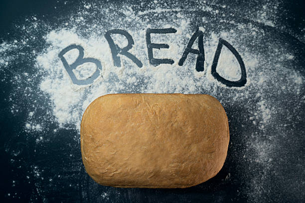 A person in an orange top is holding a freshly baked bread with both hands, showing the process of baking and enjoying homemade food