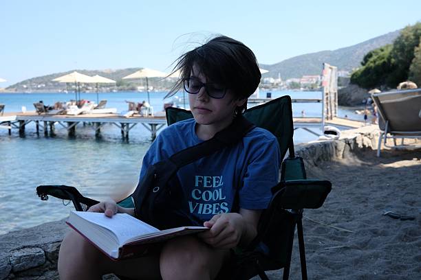 Cute Little Girls relaxing on the tropical beach and reading a book