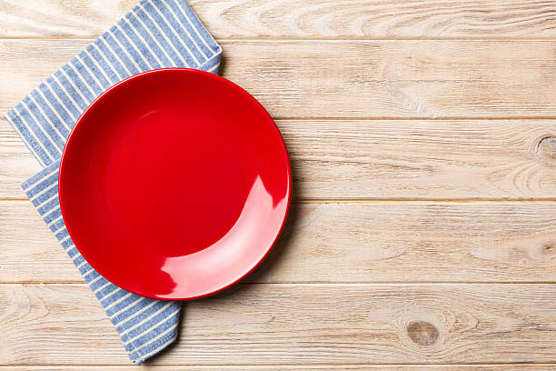 istock Top view on colored background empty round red plate on tablecloth for food. Empty dish on napkin with space for your design 2225603085