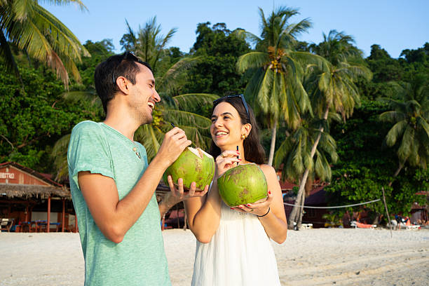 istock Happy couple drinking from coconuts on tropical beach 2225603539