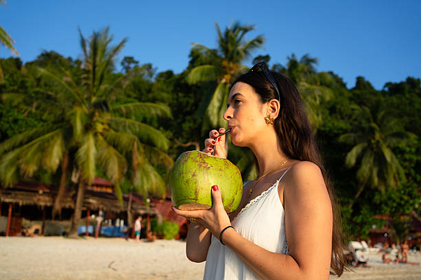 istock Tourist enjoying fresh coconut water on tropical beach 2225603566