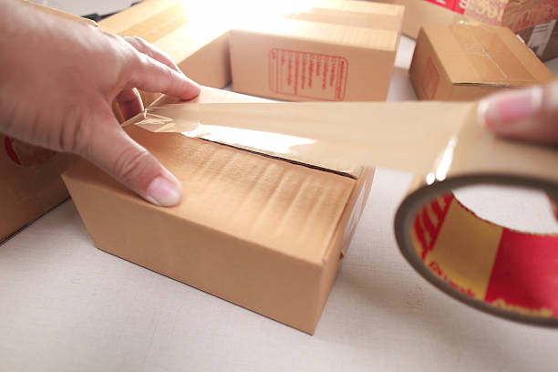 istock Hands sealing cardboard box with brown packing tape for shipping 2225604949