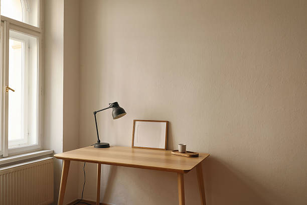 istock Minimalist workspace. Wooden desk, gray lamp, empty horizontal picture frame, poster mockup. Coffee cup on wooden tray by window. Modern Scandinavian interior, natural light. Home office setup. 2225605796