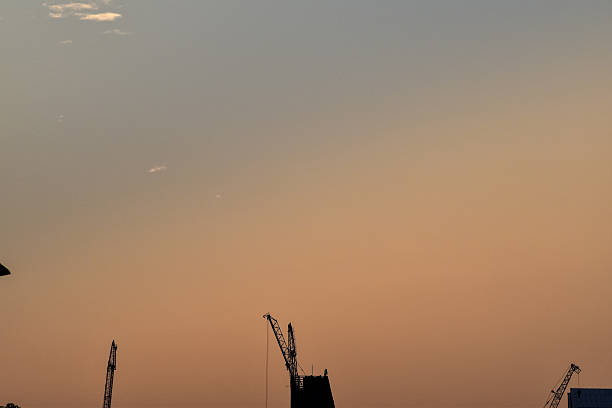 Sunset with silhouette crane on top of buildings
