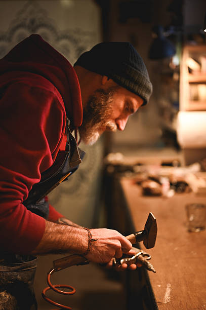 istock Craftsman working metal with hammer in workshop 2225610497