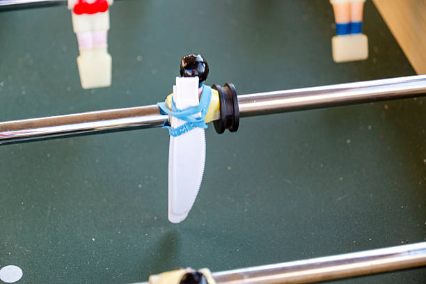 A detailed close up of a foosball table featuring a prominent white propeller placed strategically on it for enhanced gameplay experience