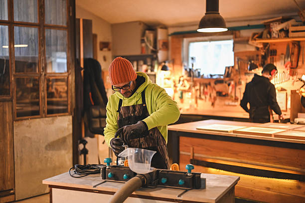 Carpenter pouring glue into woodworking machine in workshop