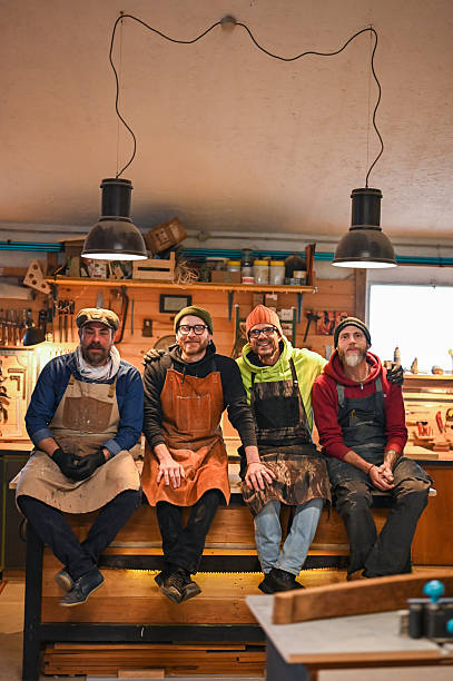 Four carpenters smiling and posing in their workshop