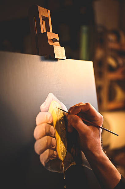 Artist painting a squeezed lemon on canvas with brush in workshop