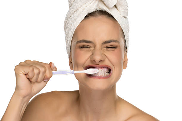 istock Young woman brushing teeth with exaggerated expression, eyes closed, studio shot on white background. 2225616438