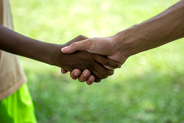 istock A white boy and a black boy are shaking hands, and the background behind them is blurred. 2225619947