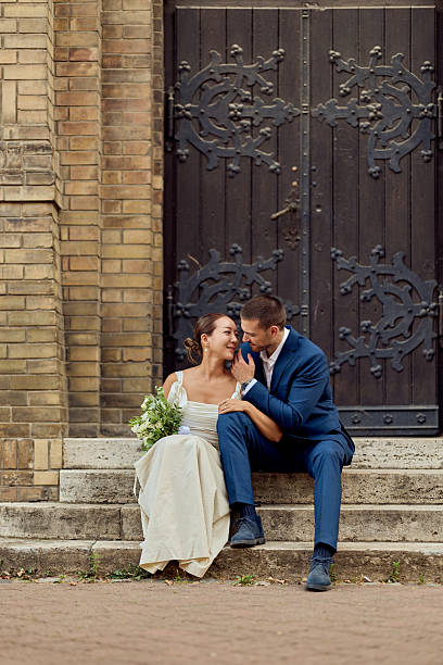 istock Romantic Wedding Couple Sitting on Steps by a Historic Brick Building 2225623049