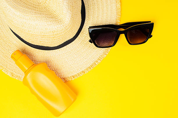 istock Hat sunglasses and sunscreen cream on yellow background summer vacation concept 2225626033