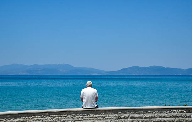 istock Old Man Sitting by the Sea 2225626769